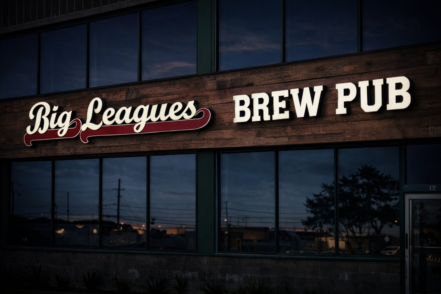 Big Leagues Brew Pub — script and block channel letters mounted on rustic wood fascia at dusk