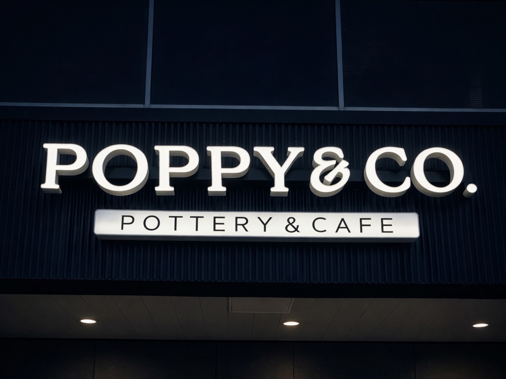 Poppy & Co. Pottery & Cafe — halo back-lit white channel letters on dark fluted fascia